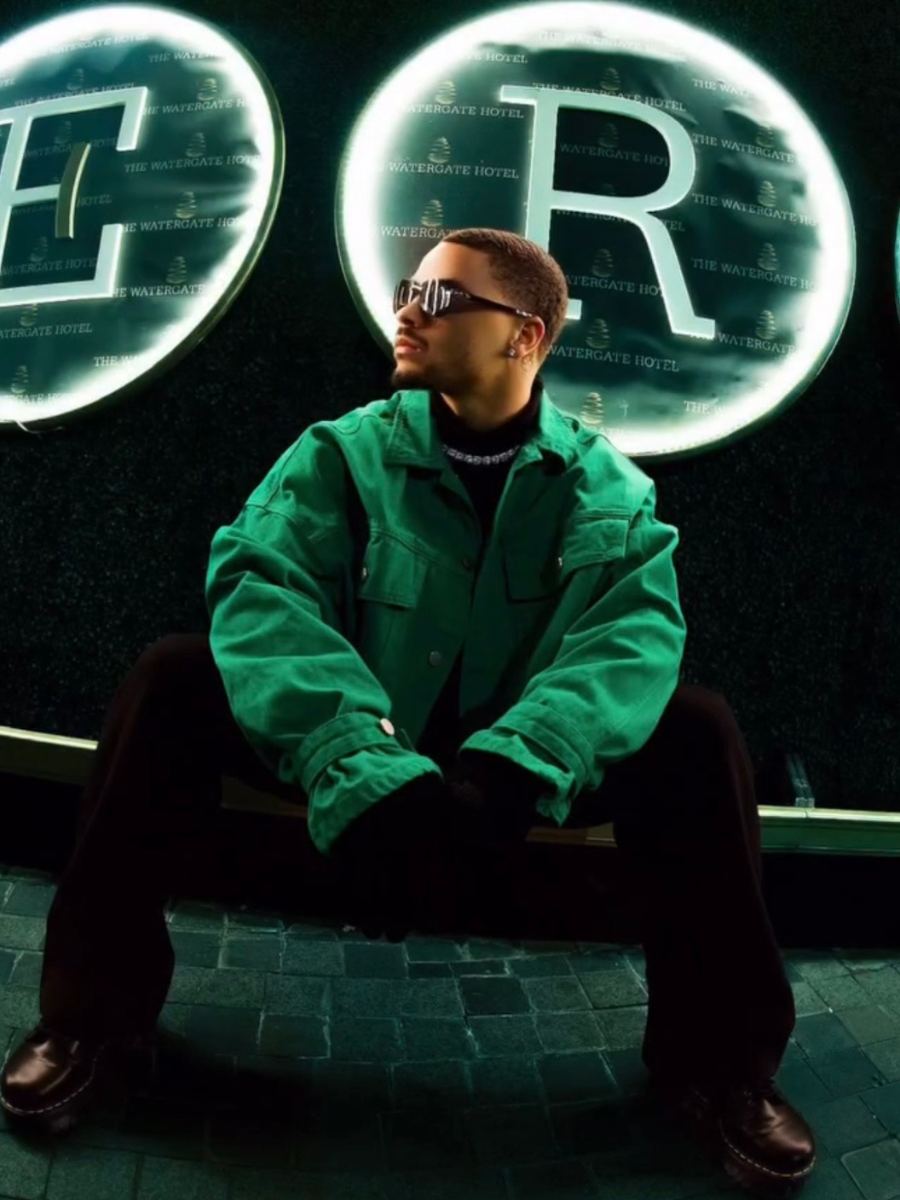 Street style portrait in a green jacket in front of a neon hotel sign